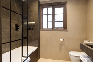 Une salle de bain moderne avec une douche à parois de verre, des toilettes et une fenêtre.