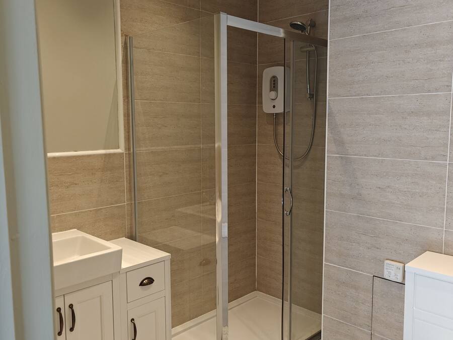 Un baño moderno con cabina de ducha de vidrio, un lavabo blanco y un inodoro.
