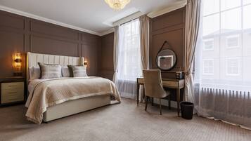 A hotel room with a bed, a desk, a chair, a mirror, and a window with curtains.