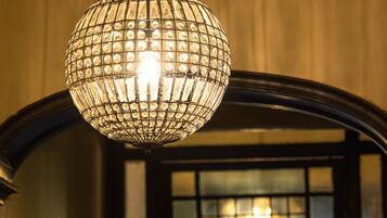 Un candelabro de cristal colgante en una habitación con un arco oscuro y una ventana con paneles de vidrio esmerilado.