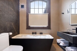 Un baño moderno con una bañera independiente, un inodoro y un tocador con espejo.