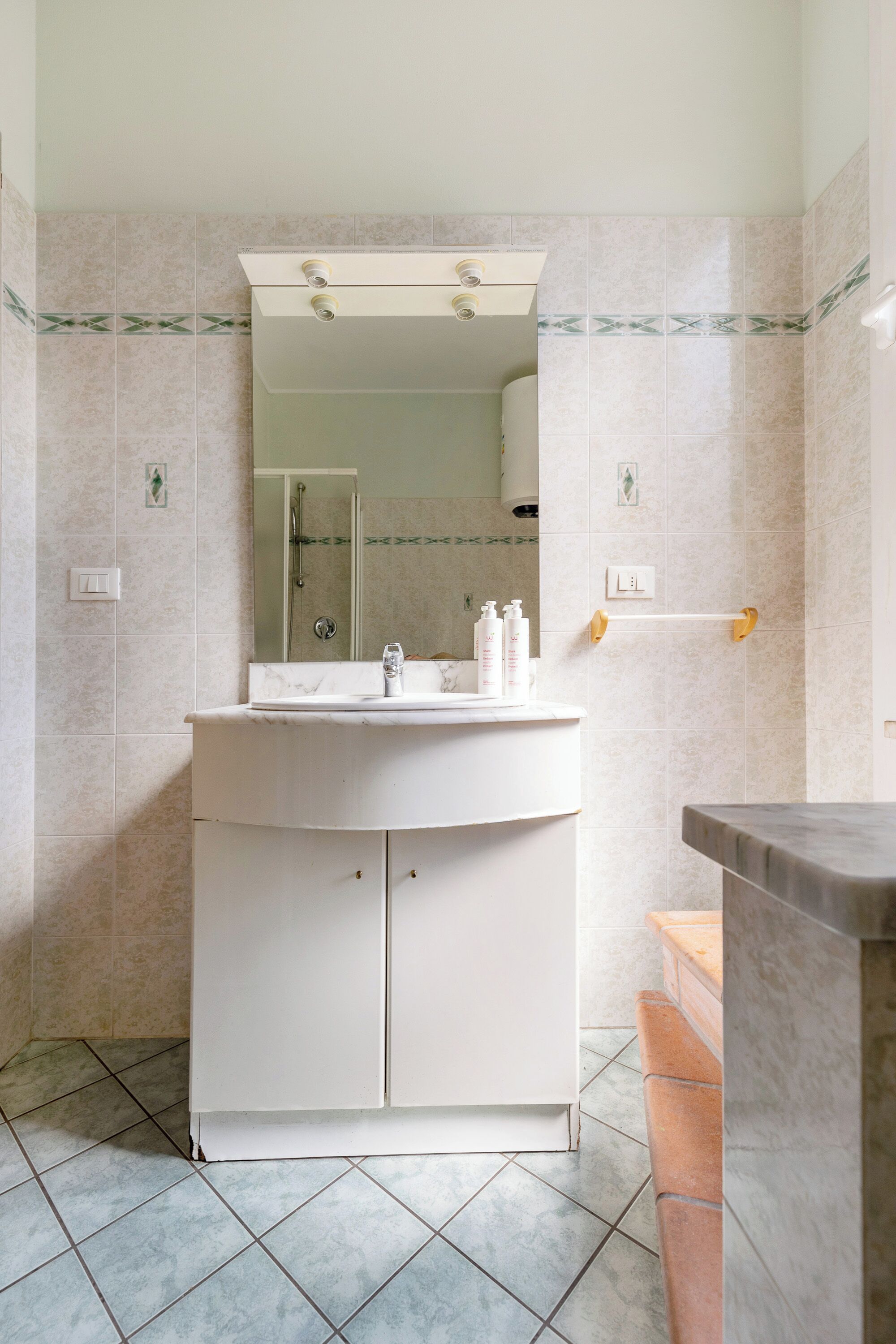 A bathroom with a white vanity, a mirror, and a shower area.