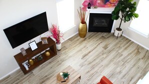 Una sala de estar moderna con una televisión de pantalla plana, una mesa de centro de madera, sofás rojos y una chimenea.