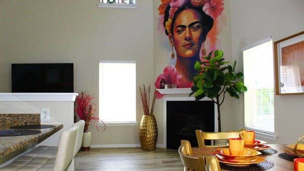 Una cocina moderna con comedor, chimenea y un cuadro grande con motivos florales en la pared.