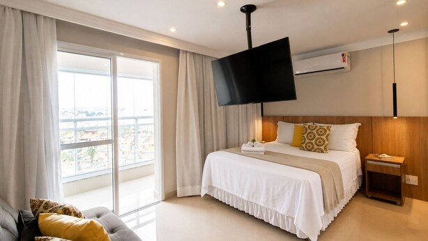 Ein Hotelzimmer mit Bett, Fernseher, Nachttisch und einer Sitzecke.