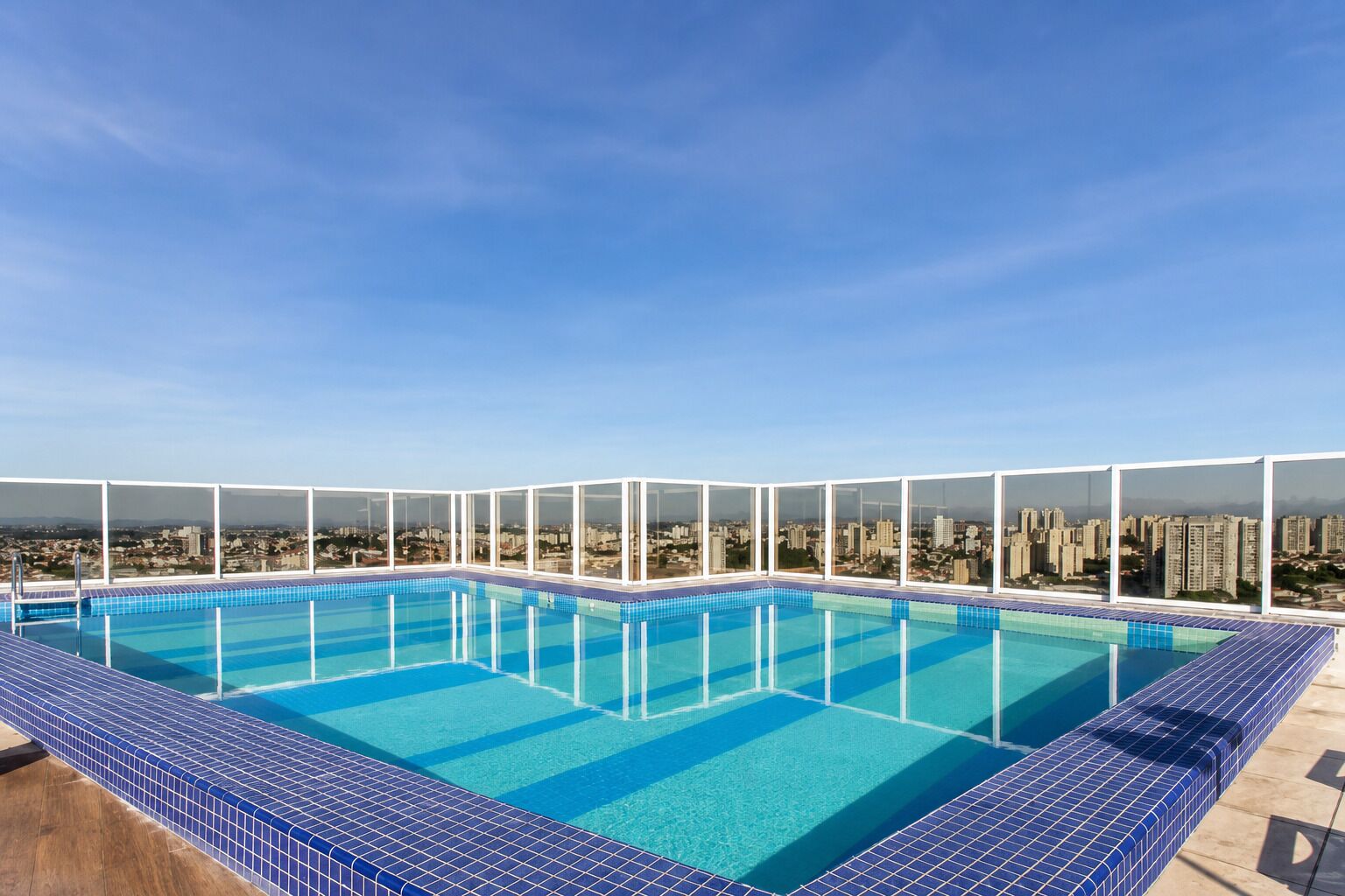 A rooftop pool with a city view, surrounded by glass railings.