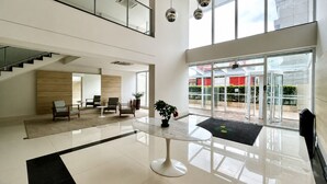 Eine geräumige Lobby mit einem zentralen Tisch, einer Sitzecke und einer Treppe zu einer oberen Ebene.