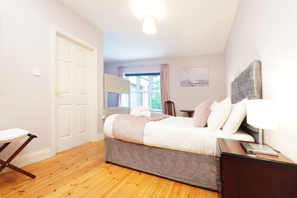 A bedroom with a bed, bedside table, lamp, and a window with curtains.