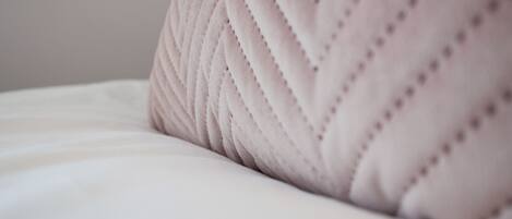 A close-up of a textured, light-colored pillow on a bed.