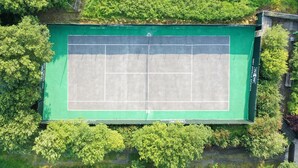 Vista aérea de una cancha de tenis rodeada de abundante vegetación.