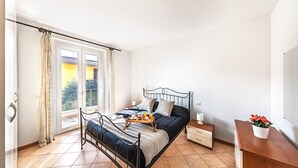 Ein Schlafzimmer mit einem Bett, einem Nachttisch, einem Fenster mit Vorhängen und Blick nach draußen.