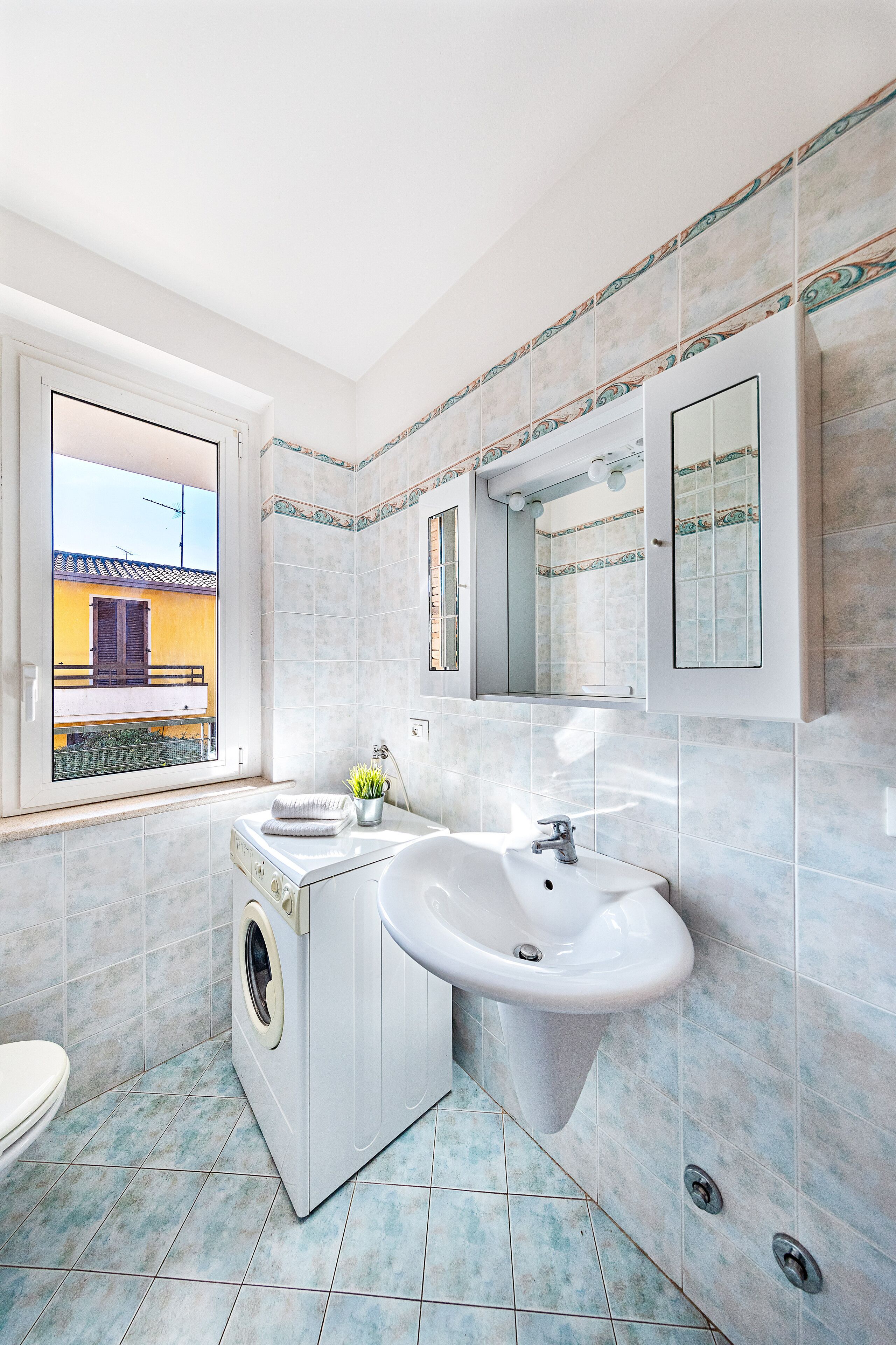 A modern bathroom with a washing machine, a sink, and a large mirror.