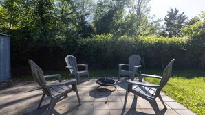 En uteplats med fyra Adirondack-stolar och en eldstad.