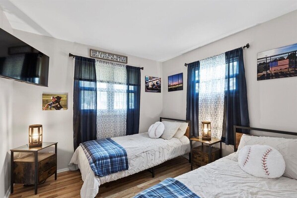 Two-bedroom suite with a modern design, featuring a bed, nightstand, and flat-screen TV.
