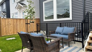 Een terras met rieten meubilair en uitzicht op omliggende huizen.