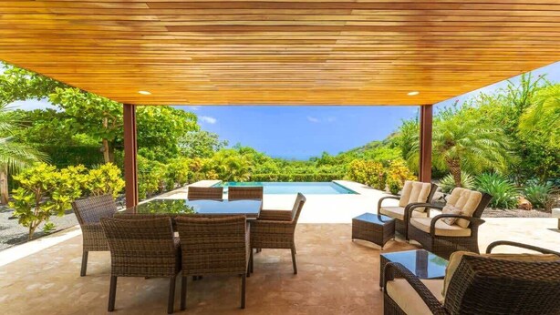An outdoor patio with wicker furniture, a pool, and lush greenery. - Casa Rebanada de Vida (Mar Vista)