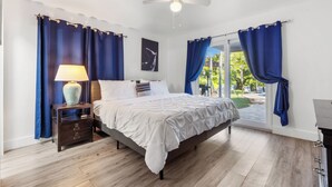 Ein Schlafzimmer mit Bett, Nachttisch, Lampe und Blick ins Freie.