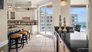A kitchen with a large island, bar stools, and a view of the beach. - Sweeping Gulf and Bay views on Clearwater Beach, 15th floor Penthouse 3 BR/3BA (Clearwater)