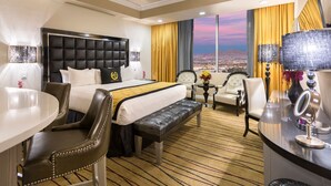 Une chambre d’hôtel avec un grand lit, un bureau, une chaise, une petite table avec une lampe et une vue sur le paysage urbain.