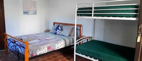 A room with a bunk bed, a single bed, and a tiled floor.