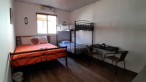 Una habitación pequeña y funcional con una cama individual, una litera, un escritorio y una silla.