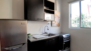 Cocina pequeña equipada con refrigerador, lavamanos y estufa.