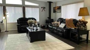 Ein Wohnzimmer mit Kamin, Ledersofas, einem Couchtisch und einem großen Fenster.