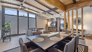 A modern dining area with a large table, grey upholstered chairs, and a contemporary ceiling design.