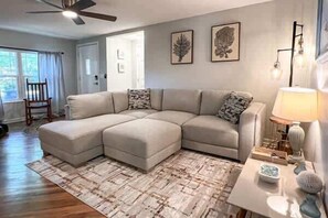 A living room with a sectional sofa, a coffee table, and a ceiling fan. - Coastal Cottage- Apalachicola- Golf Cart Rental (Apalachicola)
