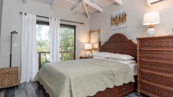 A bedroom with a wooden bed, a nightstand with lamps, a dresser, and a window with curtains.