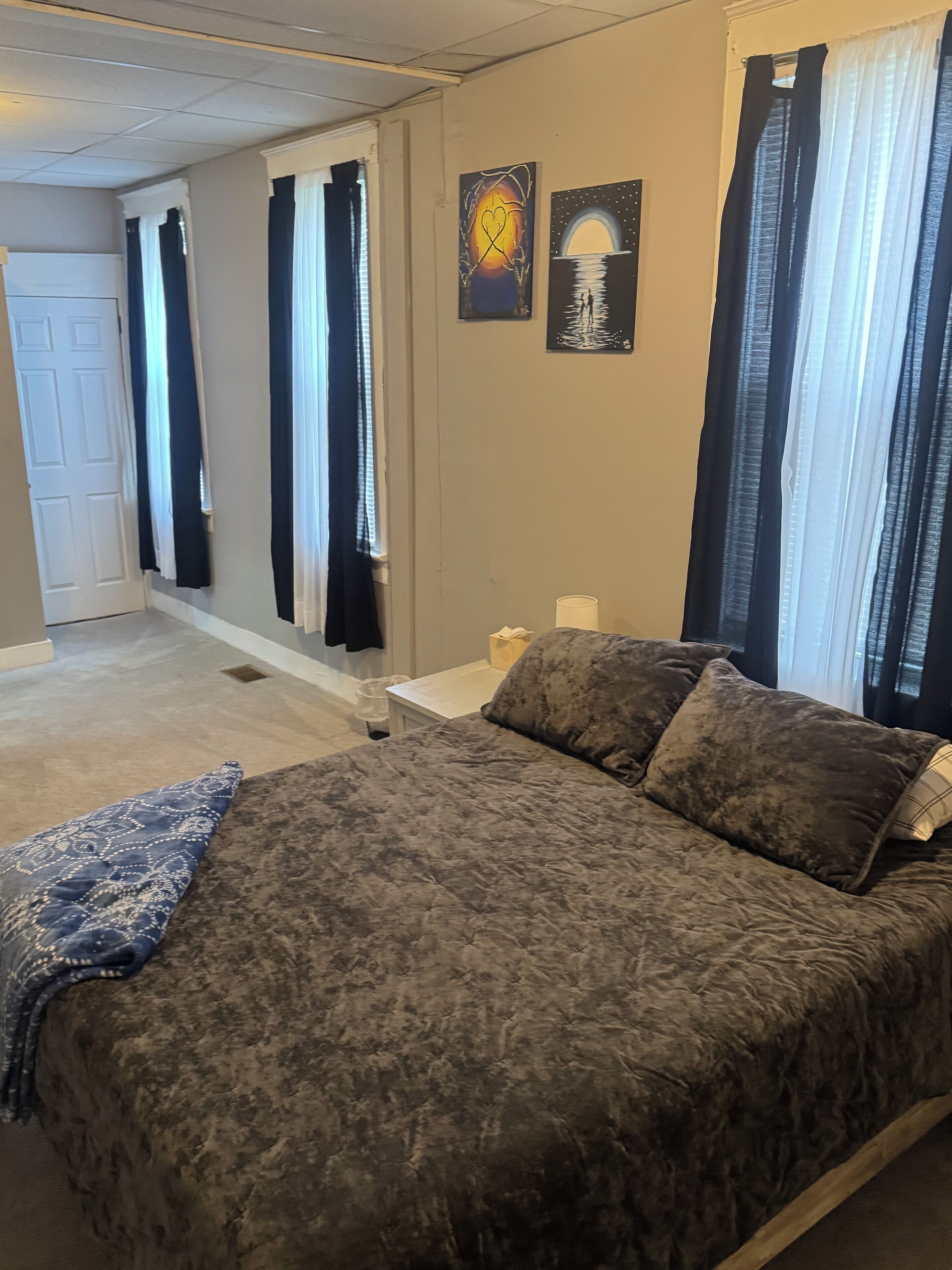 A bedroom with a large bed, a nightstand, and two wall art pieces.