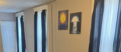 A bedroom with a large bed, a nightstand, and two wall art pieces.