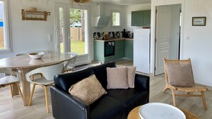 Una cocina moderna con gabinetes verdes, un refrigerador blanco y un comedor con una mesa y sillas redondas.