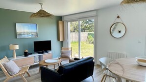 Una sala de estar moderna con televisor, sofá, mesa de comedor y sillas.
