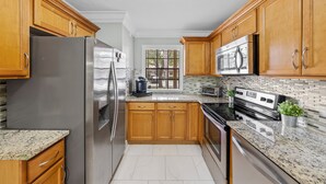 Una cocina con armarios de madera, electrodomésticos de acero inoxidable y un salpicadero de azulejos.