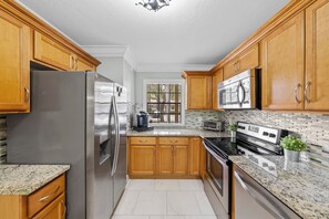 A kitchen with wooden cabinets, stainless steel appliances, and a tiled backsplash.
