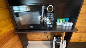 A compact kitchenette with a microwave, coffee maker, and storage for condiments. - Camping Cabins at the Red Desert RV Park (Moab)