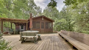 A wooden deck with a covered seating area and a small building, surrounded by trees. - Peaceful Carrollton Retreat w/ Deck & Fire Pit! (Carrollton)