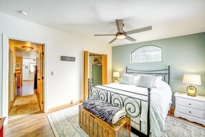 Un dormitorio con cama, mesitas de noche, un banco de madera y un ventilador de techo.