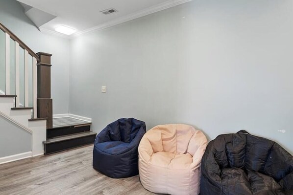 A room with a staircase, a light-colored wall, and three bean bags. - New Convenient Hub near NCSU & Downtown Raleigh
(Raleigh)