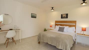 A bedroom with a bed, bedside tables, a desk, and a chair.