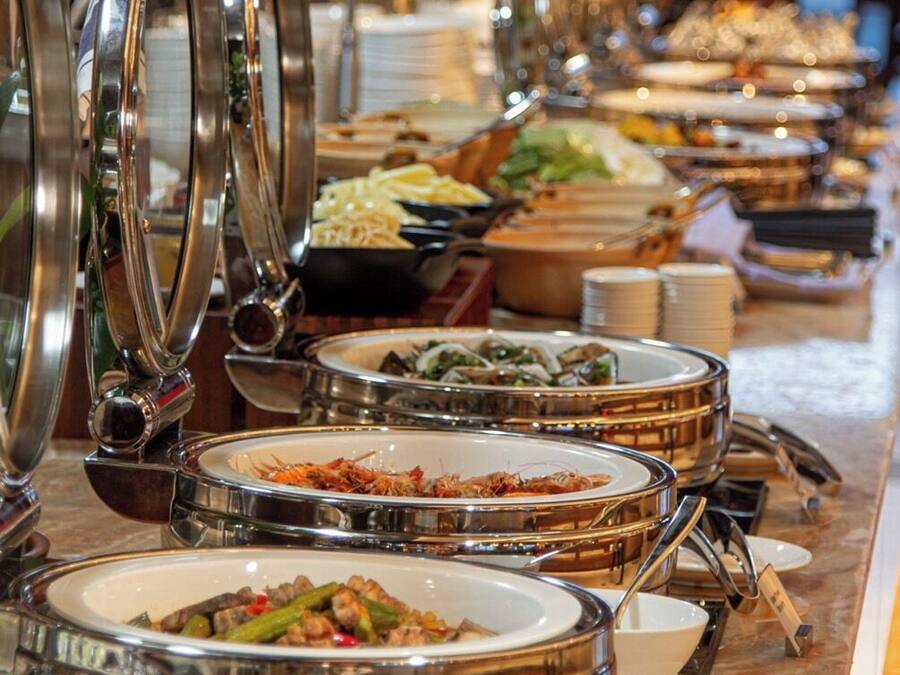 Un buffet proposant divers plats présentés dans des plats de service en métal, disposés sur un comptoir en marbre.