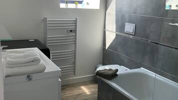 Een moderne badkamer met dakraam, ligbad en een witte wasmachine.