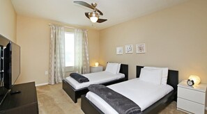 Two single beds with white linens and dark headboards, a flat-screen TV, and a wall-mounted clock.