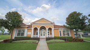 Stunning two-story building with a central entrance and arched windows, set amidst beautifully manicured lawns and trees.