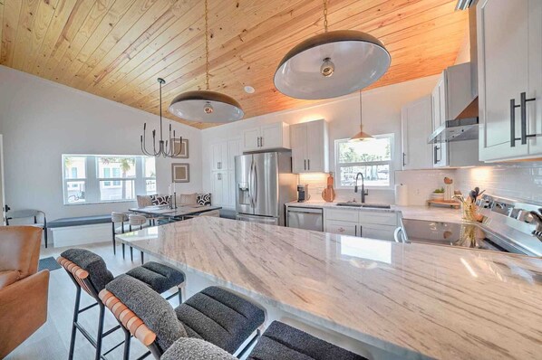 Una cocina moderna con una isla grande, electrodomésticos de acero inoxidable y techo de madera.