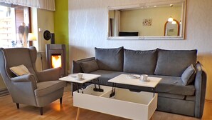A cozy living room with a sofa, armchair, coffee table, and a fireplace. - Grill, Überdachte Terrasse, Sonnenschirm, 2 Einzelbetten, 2xtv, Küche, Ww-knoten (Greifenstein)