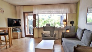 A living room with a sofa, a coffee table, a TV, and a fireplace. - Grill, Überdachte Terrasse, Sonnenschirm, 2 Einzelbetten, 2xtv, Küche, Ww-knoten (Greifenstein)