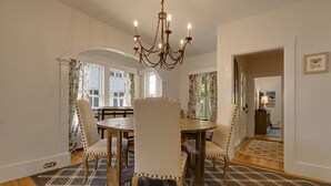 Une salle à manger avec un lustre, une table en bois et des chaises rembourrées.