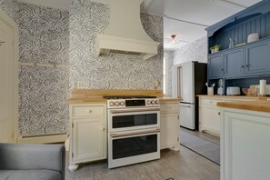 Une cuisine avec un papier peint à motifs, une cuisinière, un four et un meuble bleu.